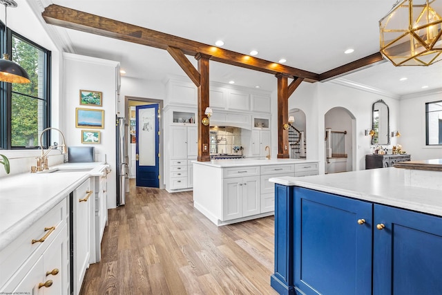 kitchen featuring light wood-type flooring, white cabinetry, sink, pendant lighting, and decorative backsplash