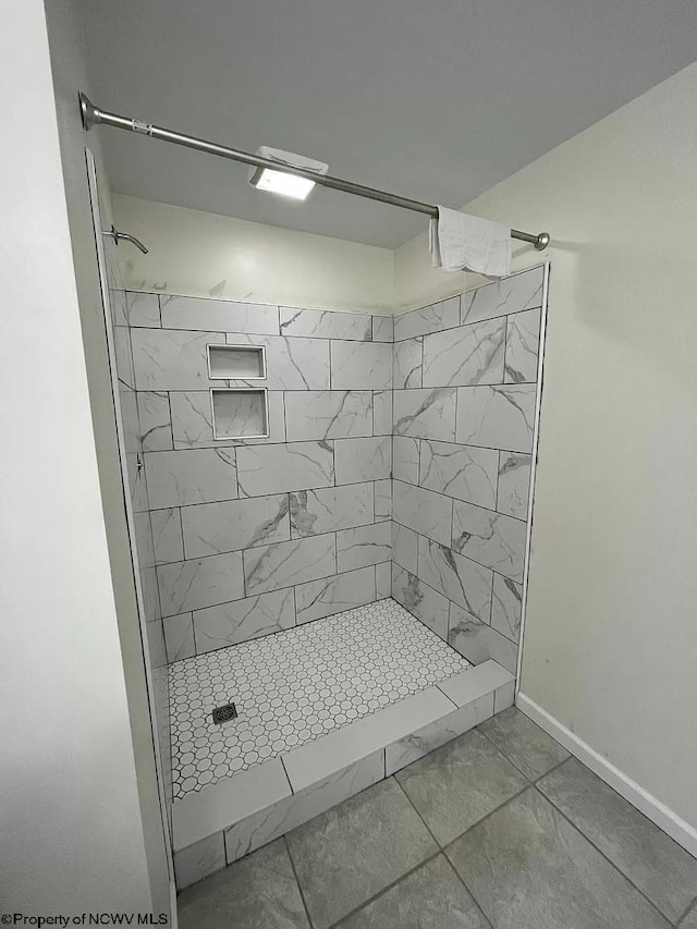 bathroom with a tile shower and tile patterned floors