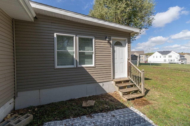 view of exterior entry featuring a lawn