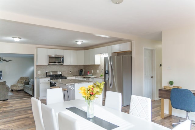 kitchen with light stone countertops, appliances with stainless steel finishes, tasteful backsplash, white cabinets, and a kitchen island