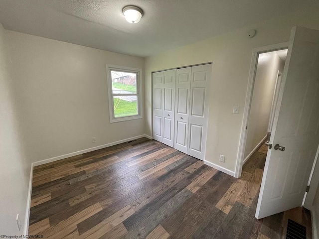 unfurnished bedroom with a closet, dark wood-type flooring, and a textured ceiling