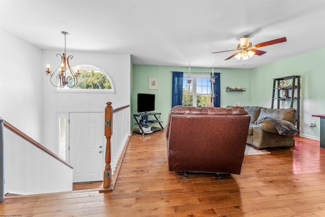 living room with ceiling fan with notable chandelier and light hardwood / wood-style floors