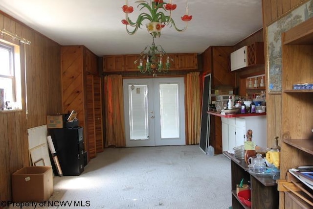 413 Green Acres Cir, Spencer, WV 25276 - dining space with wood walls, french doors, light colored carpet, and an inviting chandelier