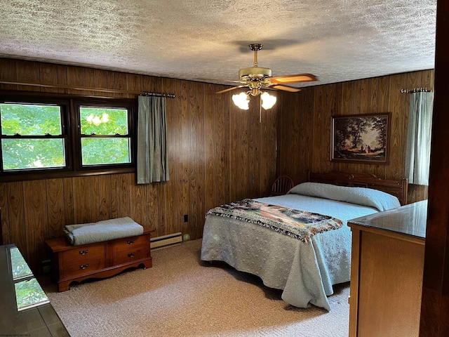 bedroom featuring wood walls, ceiling fan, baseboard heating, and a textured ceiling