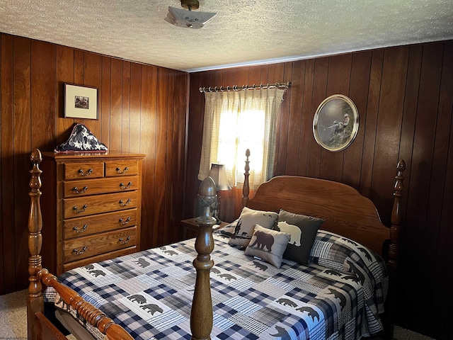 carpeted bedroom with wood walls and a textured ceiling