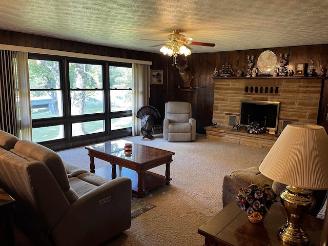 carpeted living room featuring a textured ceiling, a healthy amount of sunlight, ceiling fan, and a stone fireplace