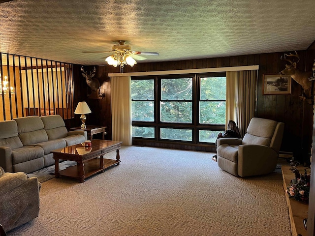 living room with a wealth of natural light, ceiling fan, wooden walls, and a textured ceiling