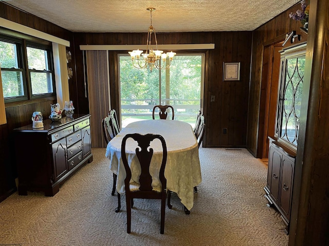 dining space with a wealth of natural light, an inviting chandelier, and wooden walls