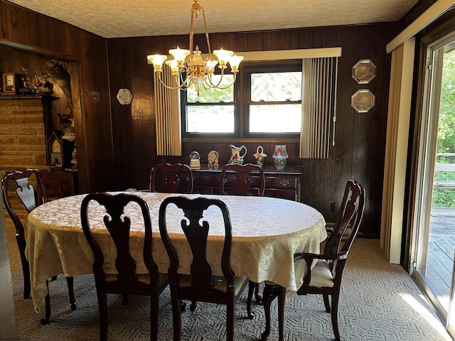 dining area featuring a healthy amount of sunlight, wood walls, an inviting chandelier, and light colored carpet