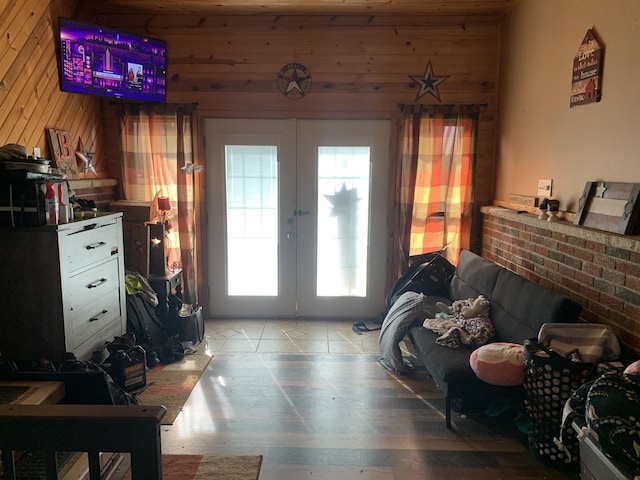 bedroom featuring wooden walls, wood finished floors, french doors, and access to outside