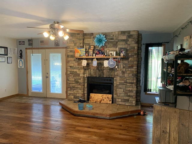 unfurnished living room with baseboards, visible vents, a ceiling fan, a fireplace, and wood finished floors