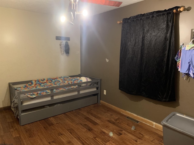 bedroom featuring baseboards, visible vents, and wood finished floors