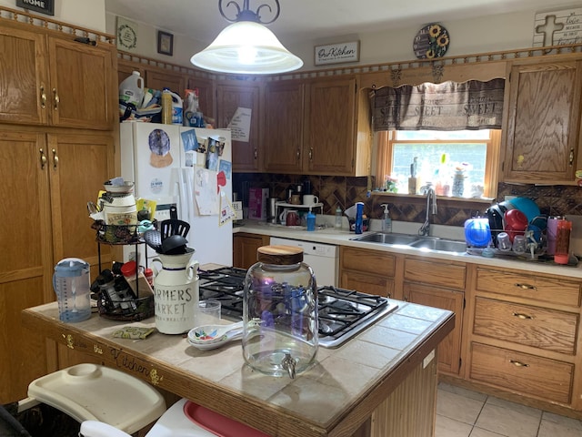 kitchen with backsplash, a sink, brown cabinetry, light tile patterned floors, and white appliances