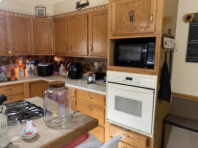 kitchen with backsplash, white oven, black microwave, and light countertops