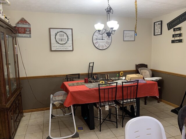 dining area featuring baseboards, a notable chandelier, and light tile patterned floors
