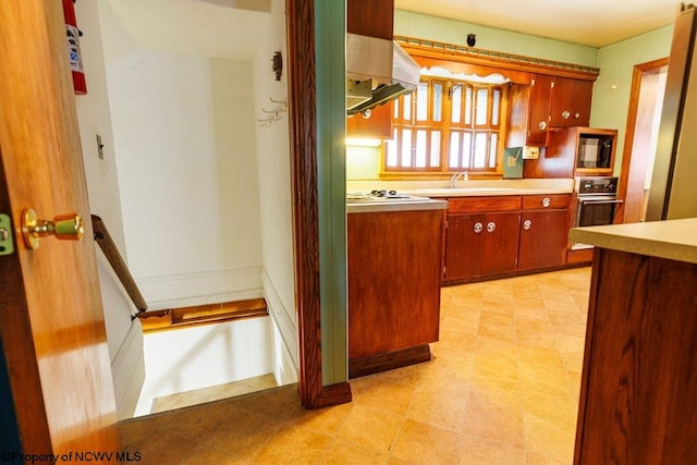 kitchen featuring range hood, oven, black microwave, sink, and white gas stovetop