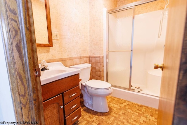 bathroom with vanity, toilet, tile walls, and walk in shower