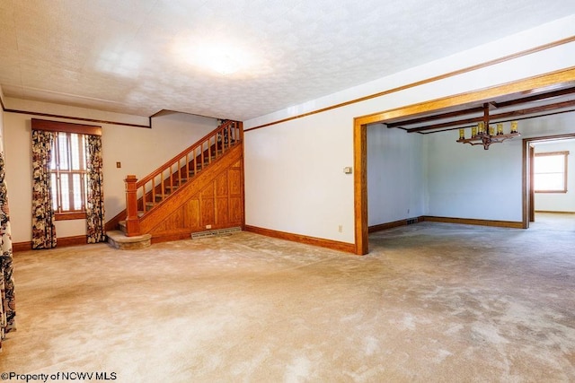 unfurnished living room with a textured ceiling, light colored carpet, and an inviting chandelier