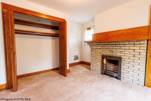 unfurnished living room featuring carpet flooring and a brick fireplace