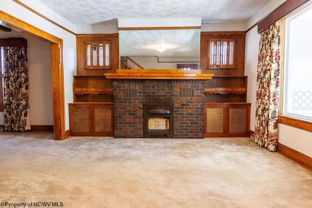 unfurnished living room featuring a textured ceiling, plenty of natural light, carpet floors, and a fireplace