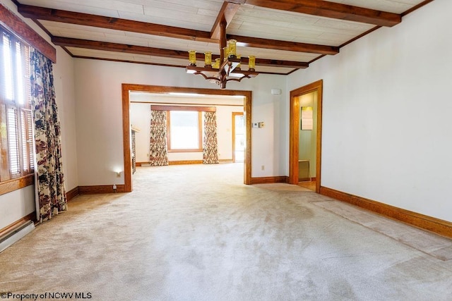 empty room with plenty of natural light, a notable chandelier, beamed ceiling, and carpet floors