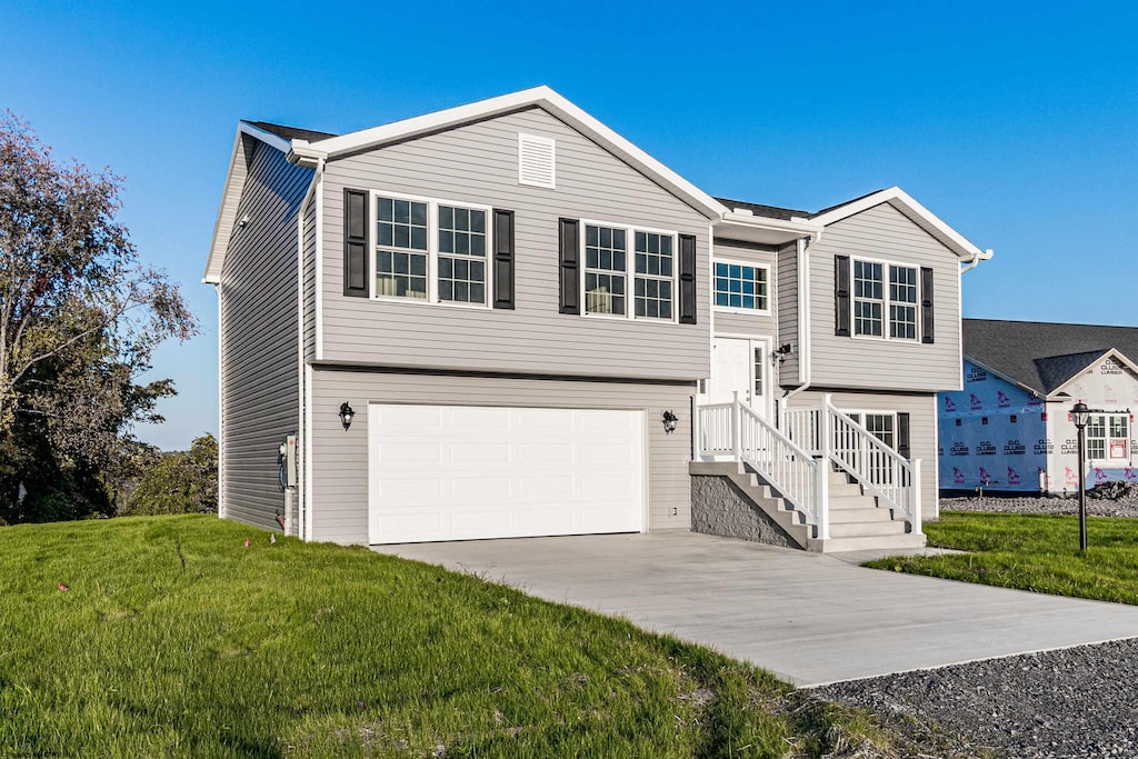 raised ranch featuring a garage and a front yard