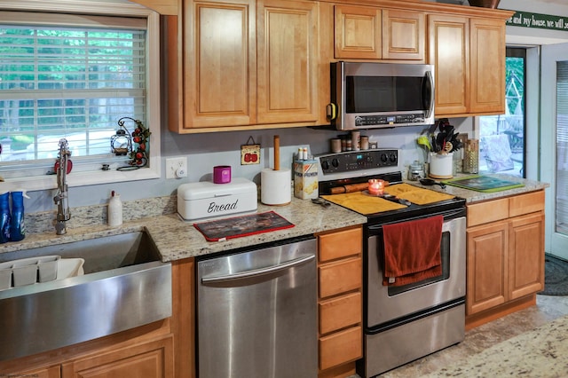 kitchen with light stone countertops, stainless steel appliances, and sink