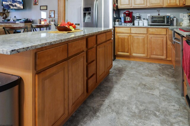 kitchen featuring stainless steel fridge with ice dispenser, a center island, and light stone countertops