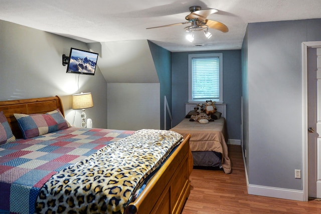 bedroom featuring lofted ceiling, ceiling fan, light wood-type flooring, and a textured ceiling