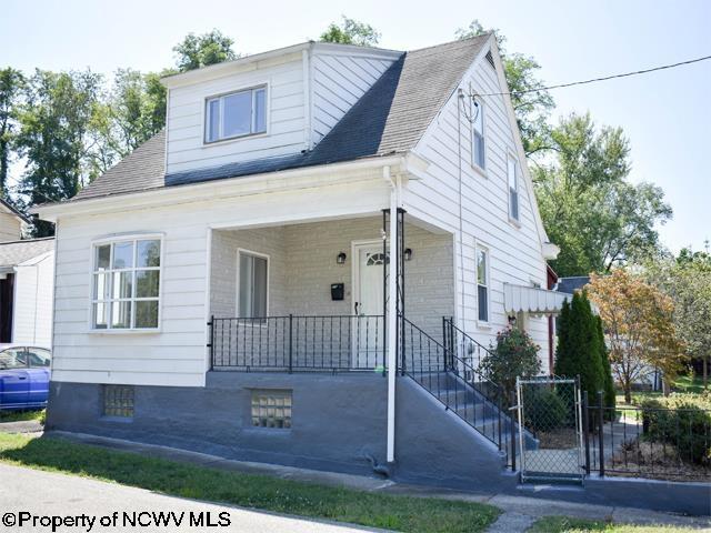 bungalow-style home with a porch, roof with shingles, and fence