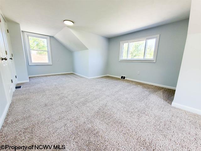 bonus room with vaulted ceiling, carpet flooring, baseboards, and visible vents