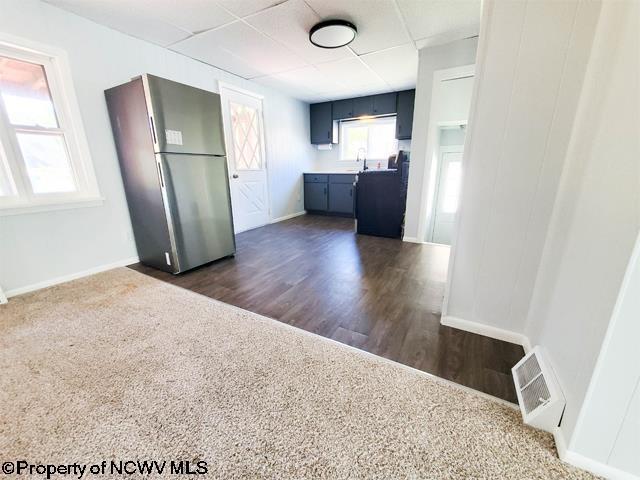 kitchen with visible vents, baseboards, dark wood-style flooring, freestanding refrigerator, and a paneled ceiling