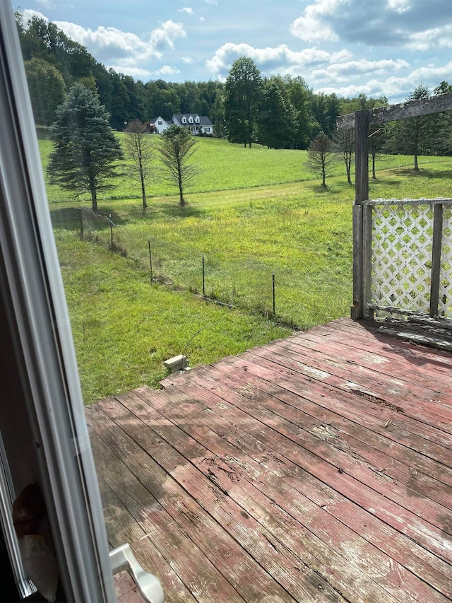 wooden deck with a rural view and a lawn