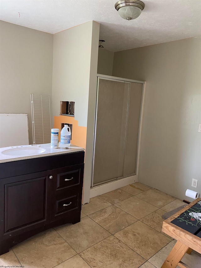 bathroom with a textured ceiling, vanity, and a shower with shower door