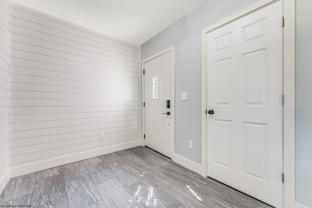 foyer featuring light wood-type flooring and wooden walls