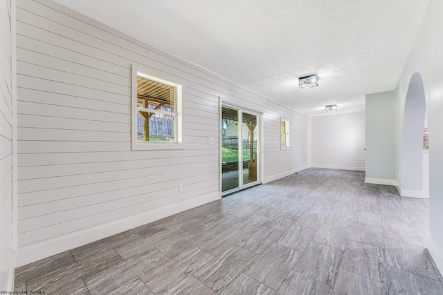 empty room with wood walls and a textured ceiling