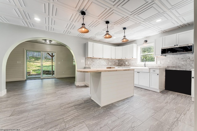 kitchen with a wealth of natural light, a kitchen island, white cabinets, and hanging light fixtures