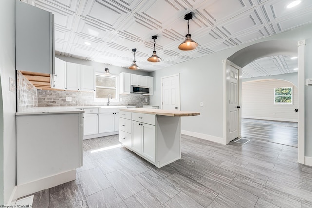 kitchen featuring pendant lighting, tasteful backsplash, a kitchen island, and white cabinets