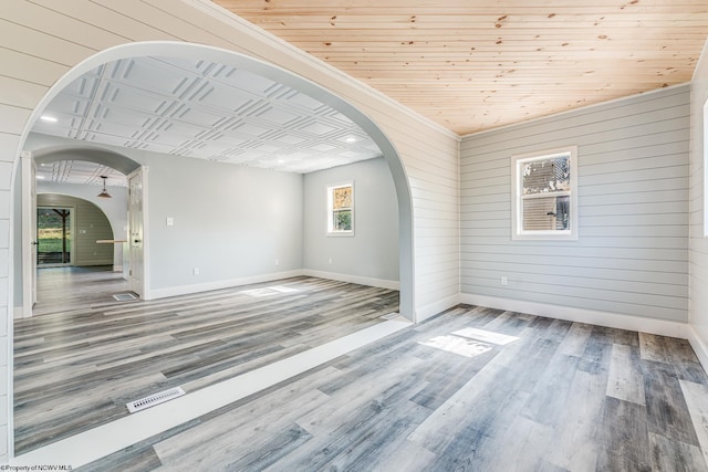 spare room with wood walls, wood-type flooring, and wooden ceiling