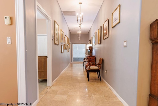 corridor with visible vents, baseboards, and a chandelier