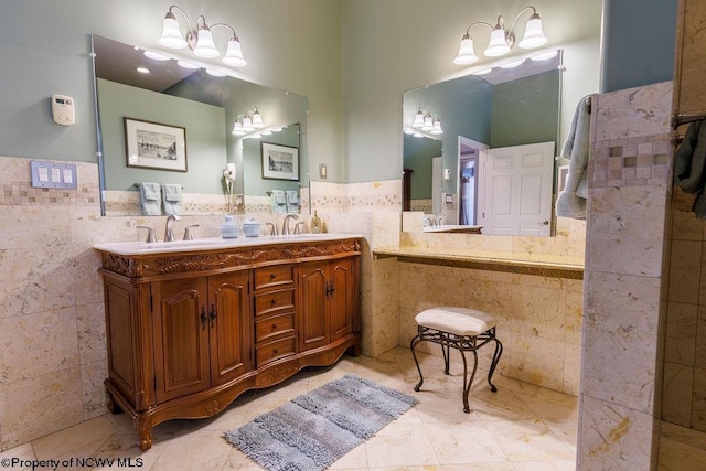 bathroom featuring tile walls, a notable chandelier, double vanity, and a sink