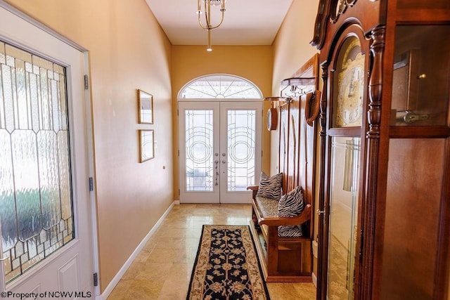 foyer entrance with light tile patterned flooring, french doors, and baseboards