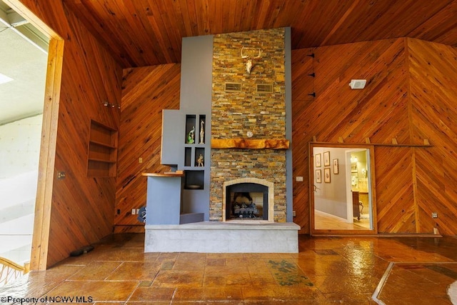 unfurnished living room featuring a fireplace, a towering ceiling, wood ceiling, and wood walls