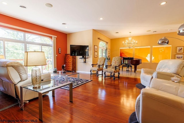 living room with visible vents, a notable chandelier, wood finished floors, and plenty of natural light