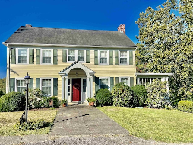 colonial house with a front yard and a chimney