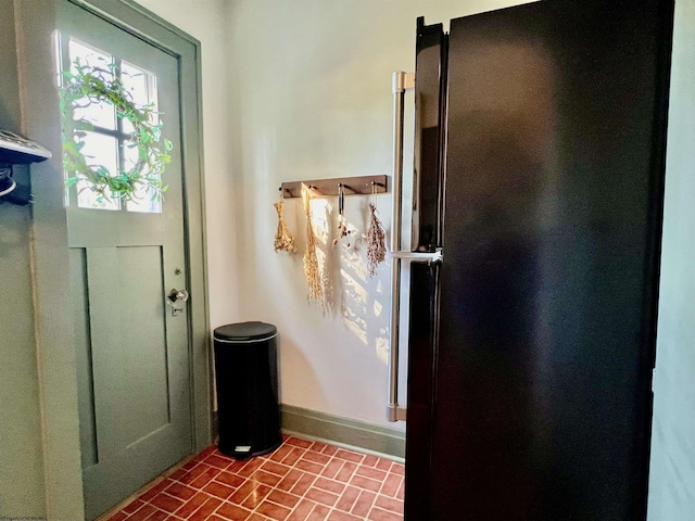 doorway to outside featuring brick floor and baseboards