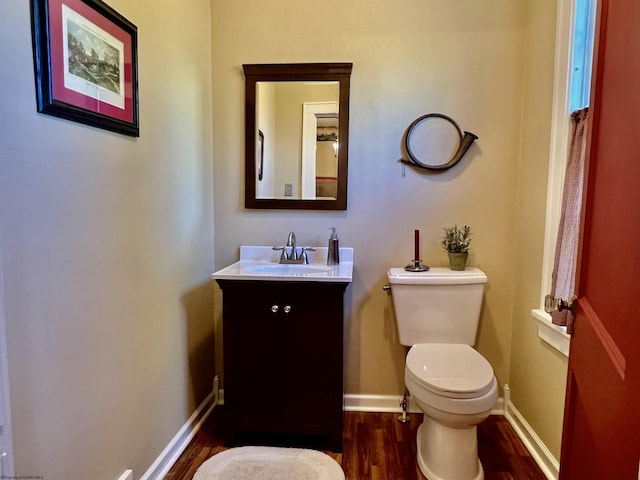 bathroom featuring toilet, vanity, baseboards, and wood finished floors