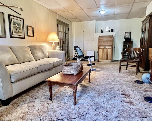 carpeted living area with a paneled ceiling