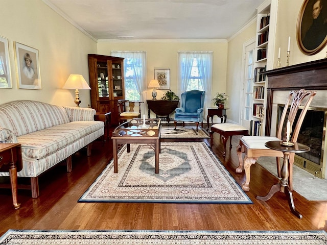 living area featuring a fireplace with flush hearth, ornamental molding, and wood finished floors