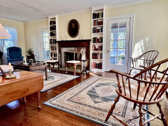 living area featuring a wealth of natural light, a fireplace, wood finished floors, and crown molding